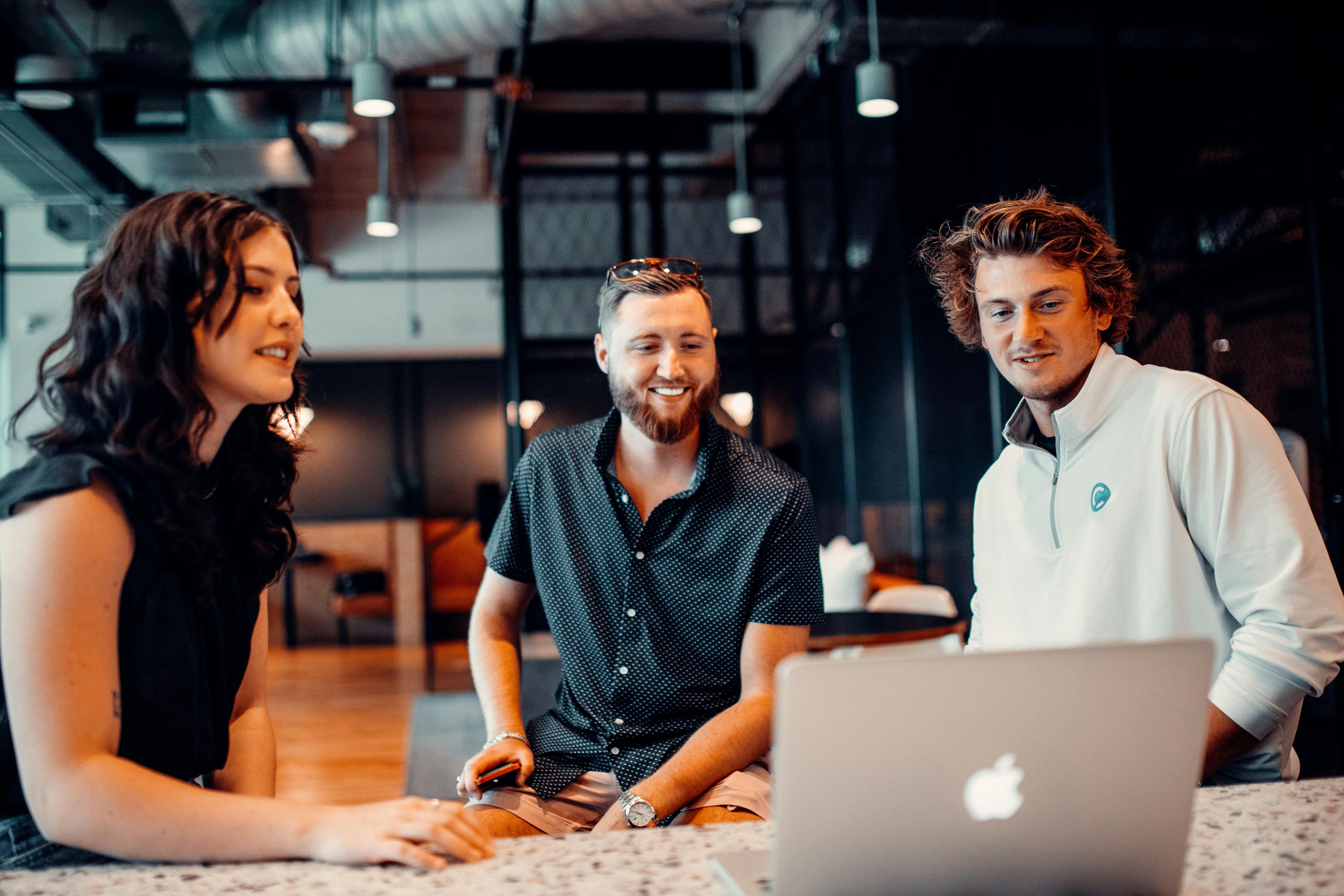Three business people collaborating around a laptop in an office.